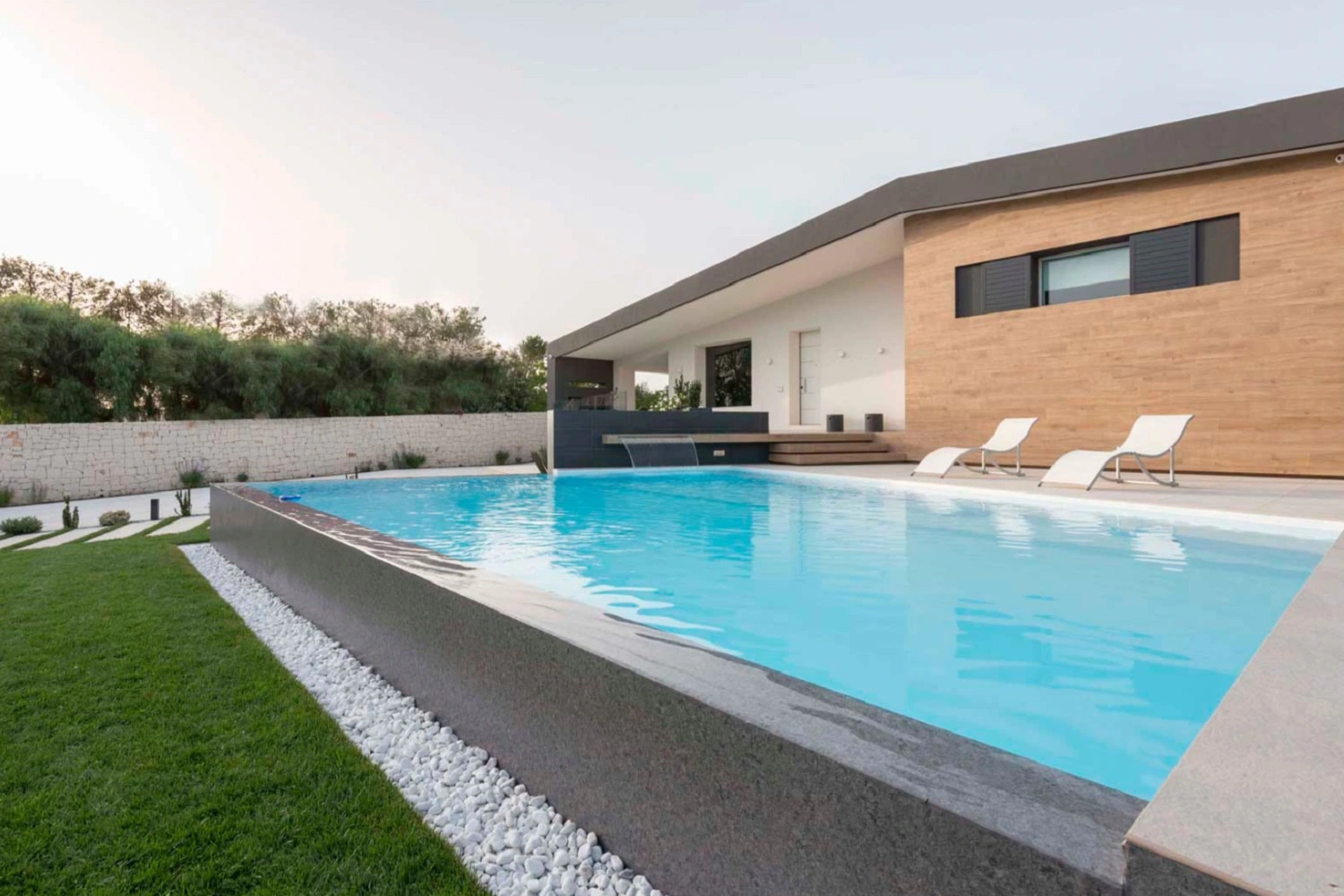 Nowoczesna rezydencja z basenem od Marazzi z białymi leżakami