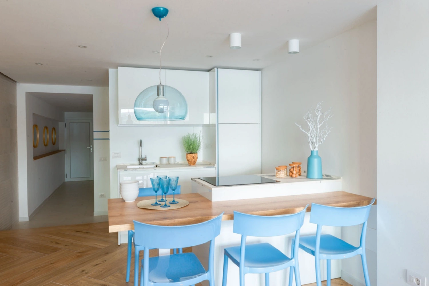 Nowoczesna przestrzeń kuchenno-jadalniana od Marazzi z akcentami błękitu i drewna