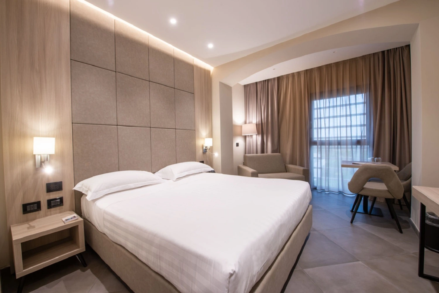 Elegancka sypialnia hotelowa od Marazzi w stonowanej kolorystyce z akcentami drewna